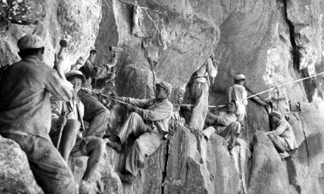 1954年，修筑康藏公路的解放軍戰(zhàn)士們?cè)谂瓋砂兜膽已露副谏媳偕街?。新華社稿 李萬(wàn)春、張加里攝